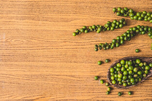 Green peppercorns on wooden background. Free space for text