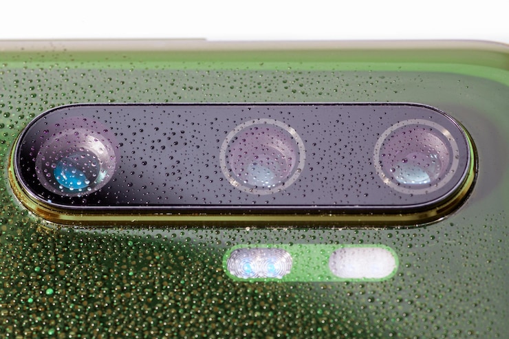 Photo green phone camera lens covered with small water drops closeup with selective focus and blur