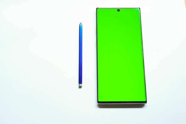 A green phone and a pen are on a white surface.