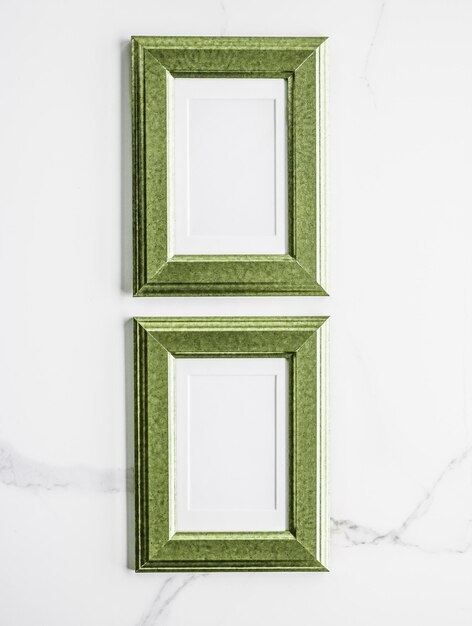 Green photo frame on marble flatlay