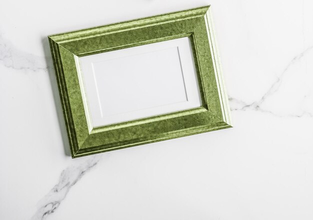 Green photo frame on marble flatlay
