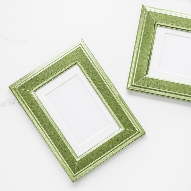 Green photo frame on marble flatlay