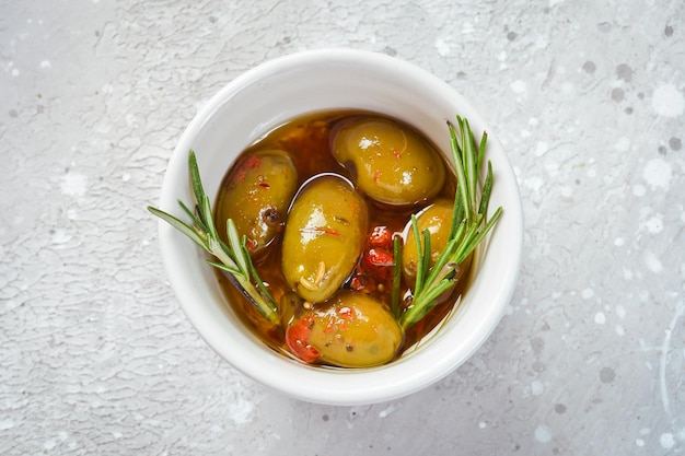 Green pickled olives in oil In a bowl on a gray stone background Free space for text