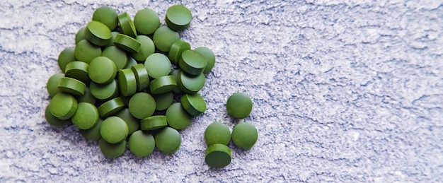 Green pills of chlorella and spirulina. Selective focus drink