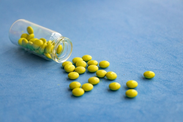 Зеленые таблетки спирулины или хлореллы на серо-синем гипсовом фоне в стеклянной миске и в деревянной ложке. Здоровая диета суперпродуктов и концепция питания детокс.