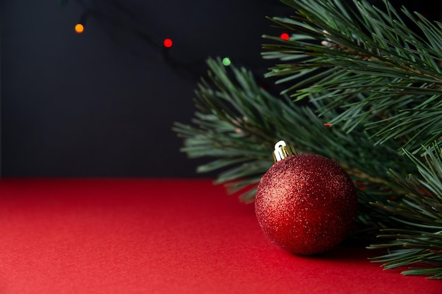 녹색 소나무 가지와 빨간색 빛나는 크리스마스 공은 빨간색 검정색 배경에 닫힙니다.