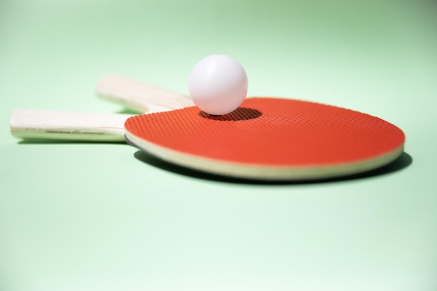 Green ping pong table with ball resting on a table tennis bat paddle