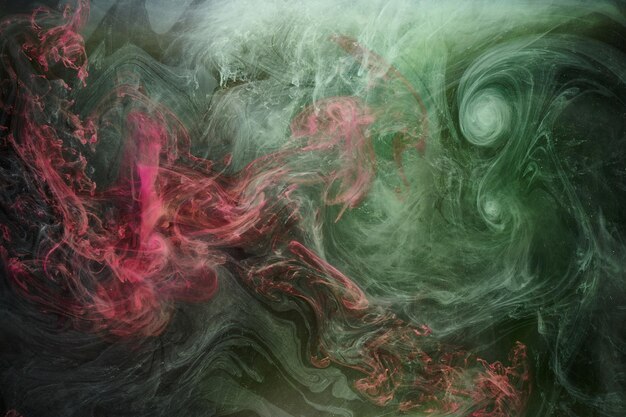 黒インクの背景に緑ピンクの煙カラフルな霧抽象的な渦巻くタッチ海海アクリル絵の具顔料水中
