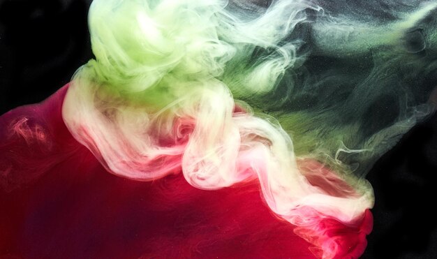 Green pink smoke on black ink background colorful fog abstract swirling touch ocean sea acrylic paint pigment underwater