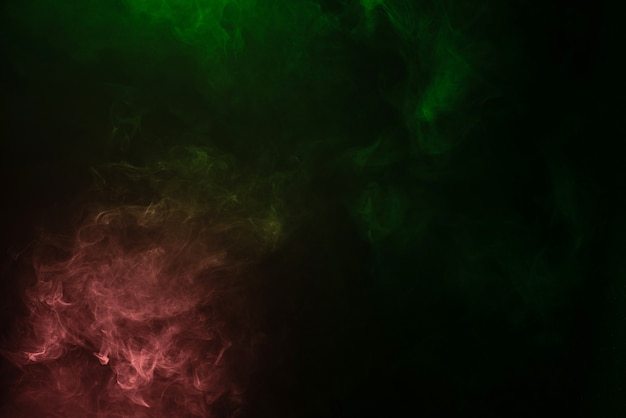 Green and pink steam on a black surface. Copy space.