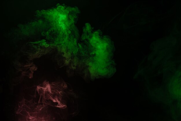 Green and pink steam on a black surface. Copy space.