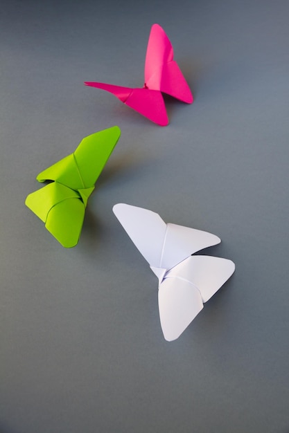 Green pink and white paper butterfly origami isolated on grey background