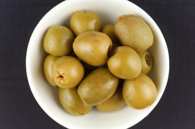 Green pitted olives in a white plate Olives closeup top view