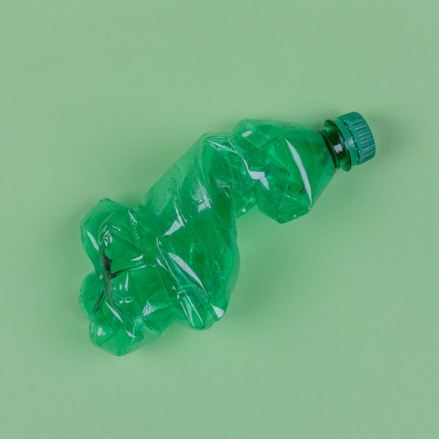 Photo a green plastic bottle on pale green background, top view.