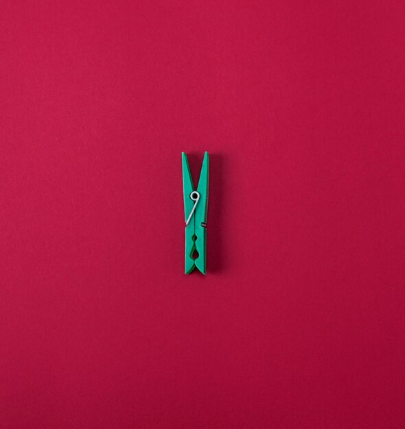 Photo green plastic clothes pin on a red background