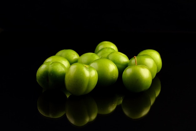 Green plums on black background