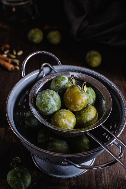 Photo green plums in gray colander