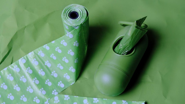 Green poop bags and green dispenser case on green background