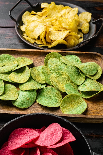 Green potato chips on old dark wooden table background