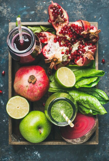 Green purple fresh juices with fruits greens vegetables in tray