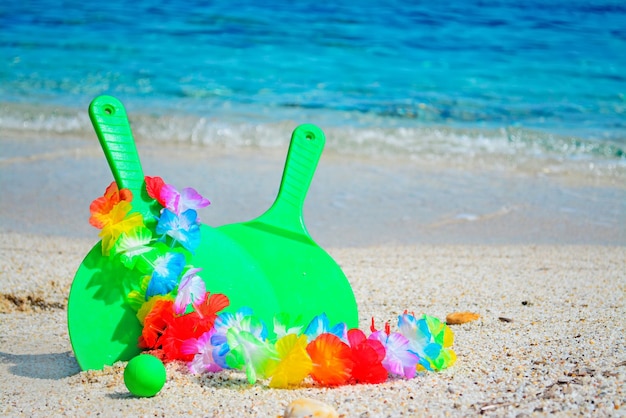 Green rackets with hawaiian necklace by the sea