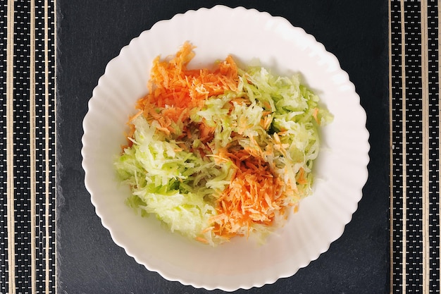 салат из зеленой редьки и моркови в белой тарелке - вид сверху