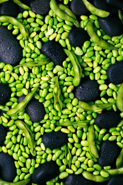 Green raw edamame soybeans and pods on black stone surface. Flat lay