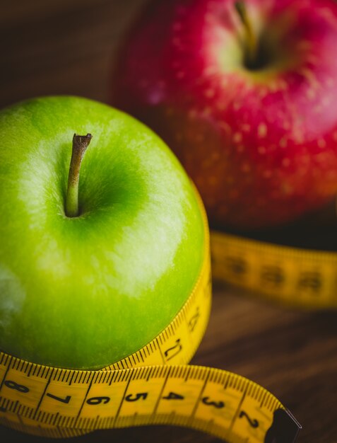 Green and red apples with measuring tape