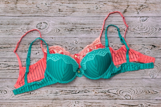 Green and red bras on wooden table. Women's sexy underwear.