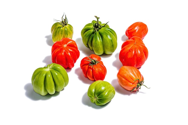 Green and red ribbed tomatoes isolated on white background American or Florentine variety