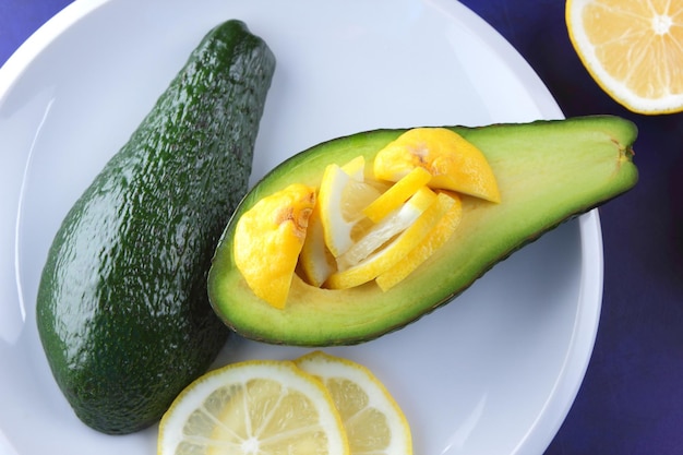 Зеленые красные желтые фрукты с цитрусами на тарелке на синем фоне Концепция вегетарианской еды Крупный план здоровой закуски