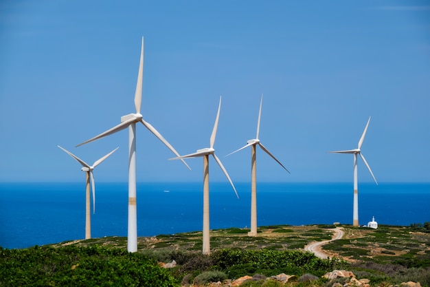 Concetto di energia alternativa rinnovabile verde - turbine del generatore eolico che generano elettricità. parco eolico sull'isola di creta, in grecia con piccola chiesa bianca