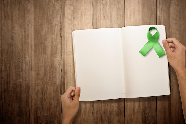 Green ribbon and empty book for copy space World mental health day concept