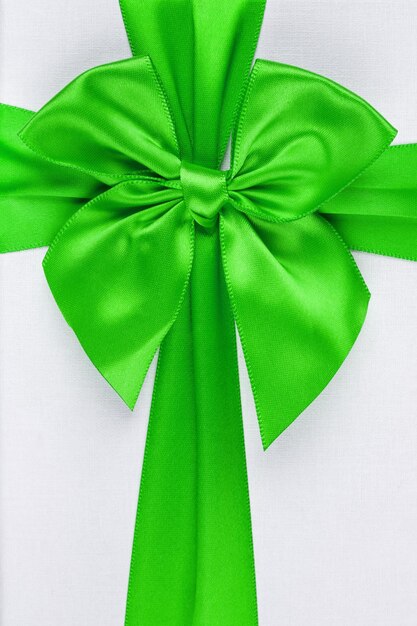 Green ribbon with bow as gift on white background