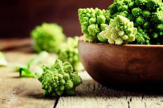 Green romanesco cauliflower in a wooden bowl vintage wooden background selective focus