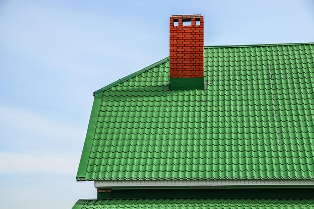 青い空を背景に家の金属プロファイルから緑の屋根