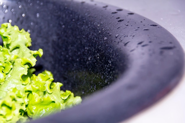 Photo green salad in a black sink for cooking delicious dietary dishes