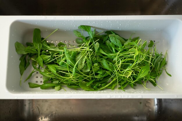 Foto insalata verde in uno scolapasta. lavare le foglie a colazione.