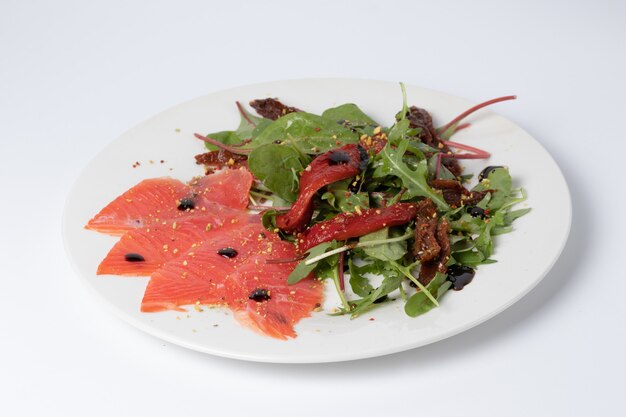 Green salad and fresh salmon on a white plate