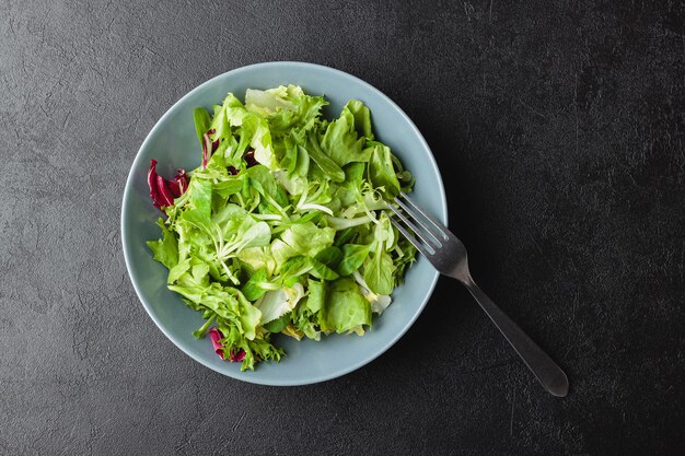 Green salad leaves in bowl on black table