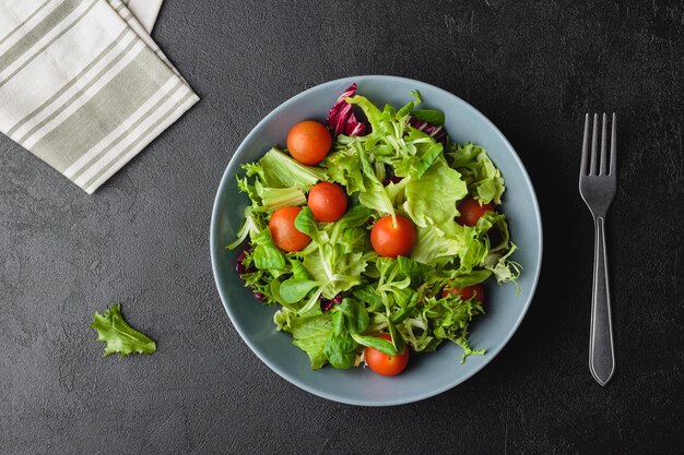 Green salad leaves in bowl on black table