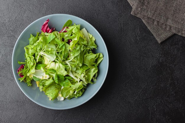 Green salad leaves in bowl on black table