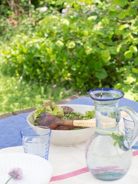 여름 정원 야외 식사 컨셉의 테이블에서 그린 샐러드와 상쾌한 물 제공