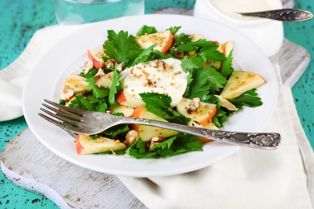 Green salad with apples walnuts and cheese on color wooden background