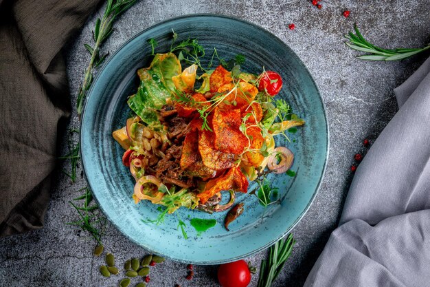 Green salad with fried potato chips tomatoes mushrooms and beef with red onion rings and arugula