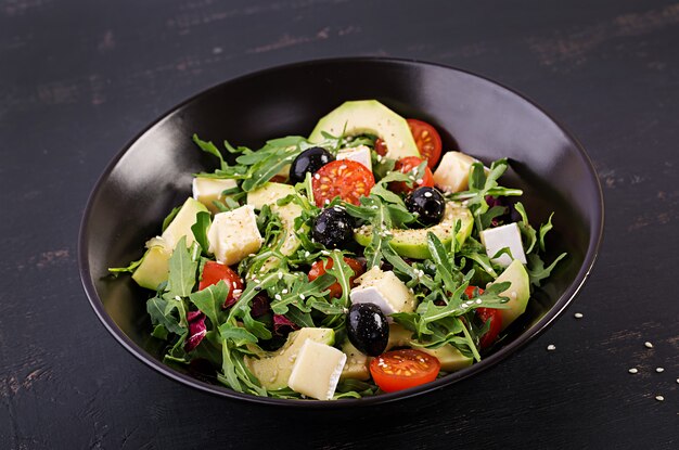 Green salad with sliced avocado, cherry tomatoes, black olives and cheese