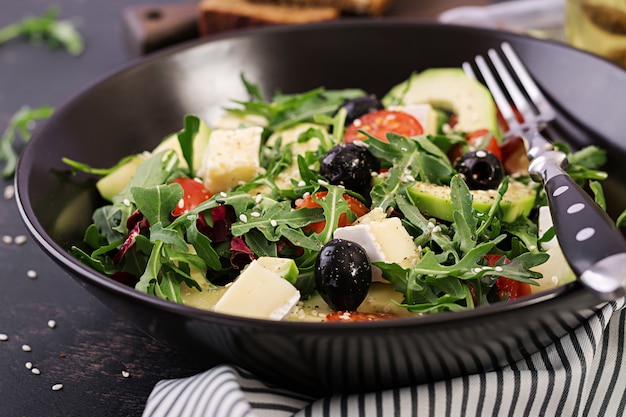 Green salad with sliced avocado, cherry tomatoes, black olives and cheese