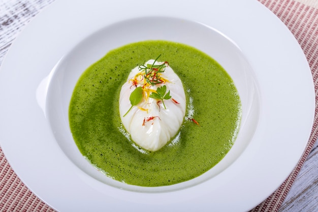 Green sauce with poached egg in white plate