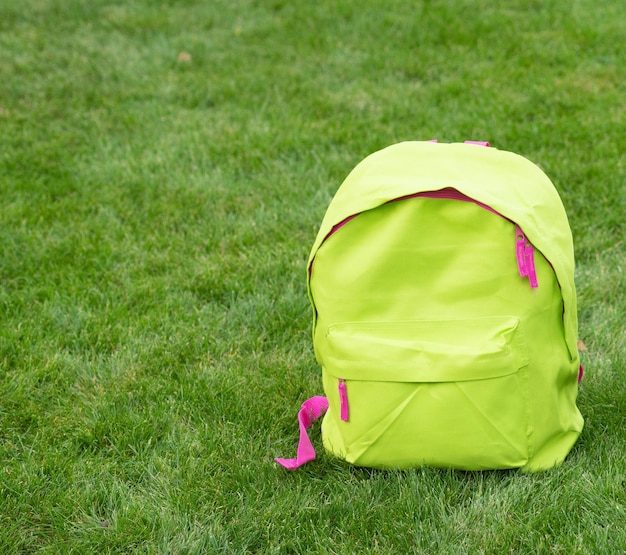 写真 草の背景のコピースペースに立っている緑の学校のバックパックランドセルバッグバッグ