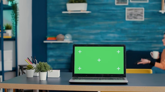 Green screen on modern laptop computer in living room, used by female student. Isolated background with blank chroma key and mockup copy space template on device with technology.